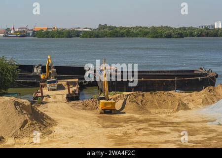 An excavator is loaded into a river vessel barges sand soil transportation of construction materials and materials along the river Stock Photo