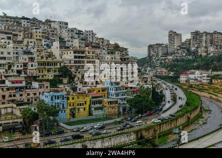 View of a residential area perched on a hill across Abou Ali River from the Citadel of Tripoli on a gloomy day in winter. Tripoli, Lebanon Stock Photo