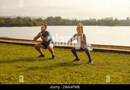 Active sporty young couple man and woman doing stretching exercising in nature. Stock Photo