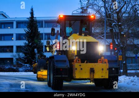 Yellow motor grader Vammas RG 286 removing snow from street early in the morning. Salo, Finland. December 29, 2023. Low light photo. Stock Photo