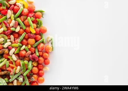 Frozen vegetables on a white background with copy space. Frozen assorted vegetables covered with snow and ice ready to cook. Stock Photo