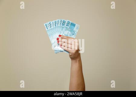 several hundred real bills - money from Brazil in a womans hand with red nails Stock Photo