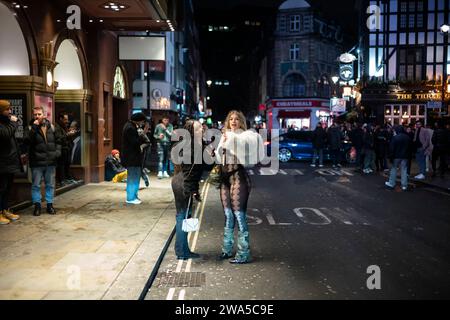 People enjoy the New Years Eve party atmosphere whilst out amongst the crowds in Soho, the capital's West End area, London, England, United Kingdom. Stock Photo
