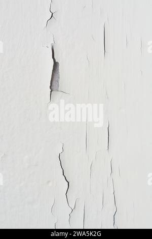 close-up of cracked wall, white wall surface with paint peeling off, non standard interiors in vertical orientation Stock Photo