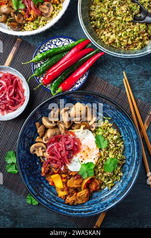 Ketogenic diet bowl with organic cauliflower and broccoli rice, stir fried chicken, mushrooms, egg and onions. Gluten free healthy food. Stock Photo