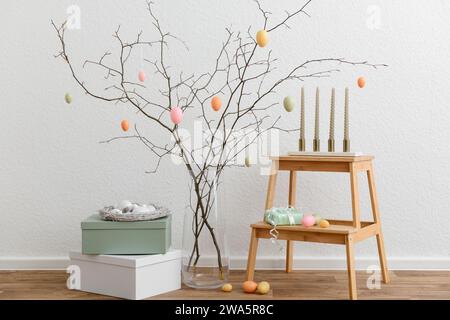 Festive composition with tree branches, painted eggs and candles for Easter celebration Stock Photo