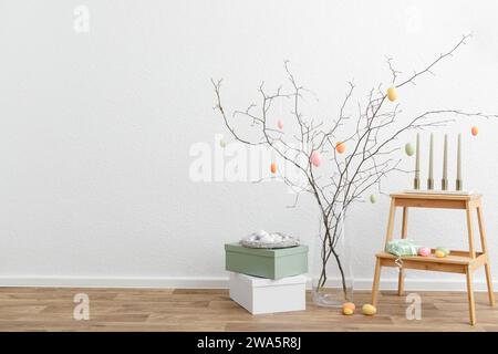 Festive composition with tree branches, painted eggs and candles for Easter celebration Stock Photo
