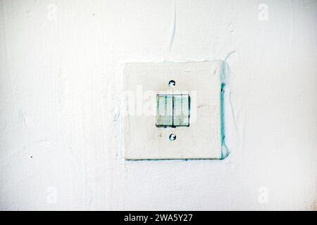 An old light switch on the wall. Electrical switching. Painted switch. Stock Photo