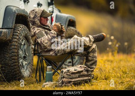 Caucasian Man Wearing Camouflage Drinking Coffee While on Off Road Outdoors Adventure Stock Photo