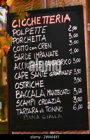 CICCHETTERIA means Snack bar in Italian and list of Italian cuisine foods meaning meatballs porchetta breaded sardines anchovies oysters cod and other Stock Photo