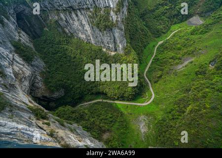There is a path in the lush green valley. The Three Natural Bridges are a series of natural limestone bridges, Chongqing. Stock Photo