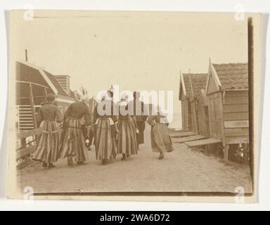 Men, women and a girl in traditional costumes in Volendam, in the distance the Zuiderzee, c. 1900 - c. 1910 photograph  Volendam photographic support salted paper print adult man. adult woman. child. folk costume, regional costume Volendam. Zuiderzee Stock Photo