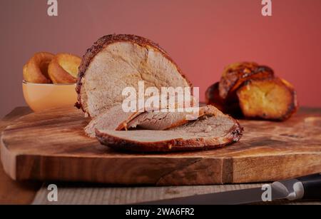 Beef roast joint that has been sliced with some Yorkshire puddings and roast potatoes in the background. Stock Photo