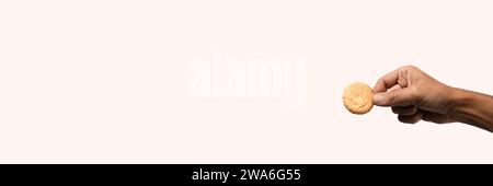 Male hand holding a biscuit banner on light pink Stock Photo
