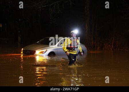 Hathern, Leicestershire, UK. 2nd January 2024. UK weather. A Fire Fighter walks away after checking inside a car stranded in flood water. High winds and heavy rain are battering a large swathe of the UK as the small but potent Storm Henk hits.  Credit Darren Staples/Alamy Live News. Stock Photo