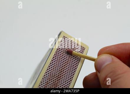 A close up photo of someone lighting a match against the side of a match box. Stock Photo