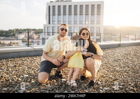 Mom and dad holding dog while crouching next to daughter Stock Photo