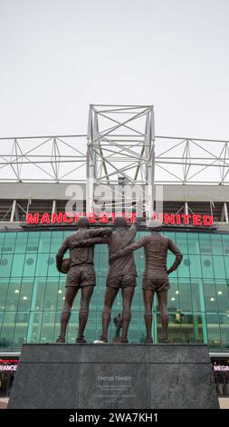 United Trinity statue featuring Manchester United legends George Best, Denis Law and Sir Bobby Charlton pictured facing Old Trafford stadium and the S Stock Photo