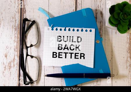 Build back better text on a notepad page on a gray background near banknotes and a magnifying glass Stock Photo