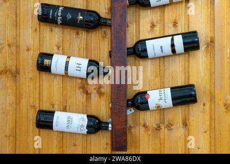 Évora, Alentejo, Portugal. November 26, 2022. Display of Alentejo wine bottles on wall-mounted rack in a rustic restaurant. Stock Photo