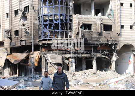 Gaza. 7th Oct, 2023. People walk past destroyed buildings in Gaza City, on Jan. 2, 2024. The death toll of Palestinians has exceeded 22,000 after the outbreak of the Israel-Hamas conflict on Oct. 7, 2023, the Hamas-run Health Ministry said on Tuesday. Credit: Mohammed Ali/Xinhua/Alamy Live News Stock Photo