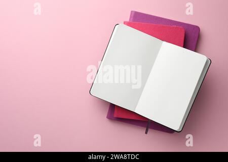 Different notebooks on light pink background, top view. Space for text Stock Photo