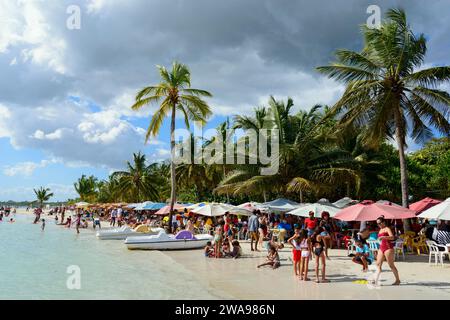 Beachgoers relax under colourful umbrellas next to the calm sea, Boca Chica, Santo Domingo Province, Dominican Republic, Hispaniola, Caribbean, Americ Stock Photo