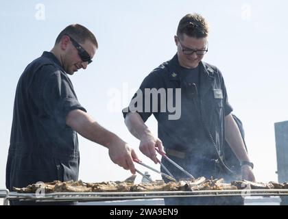 US military forces. 180708GY005-0007 ATLANTIC OCEAN (July 8, 2018) Chief Hull Maintenance Technician John Parker, left, and Master Chief Fire Controlman Jacob Streufert prepare food during a steel beach picnic on the flight deck aboard the Nimitz-class aircraft carrier USS Harry S. Truman (CVN 75). Harry S. Truman is currently deployed as part of an ongoing rotation of U.S. forces supporting maritime security operations in international waters around the globe. (U.S. Navy photo by Mass Communication Specialist 3rd Class Gitte Schirrmacher/Released) Stock Photo