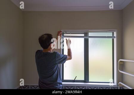 Man installing bathroom blinds. Home renovation project. Stock Photo