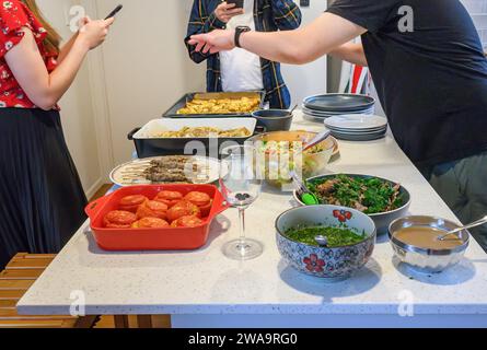 Young people holding smartphones taking photos of festival food on the kitchen benchtop. Home cooking and entertainment concept. Stock Photo