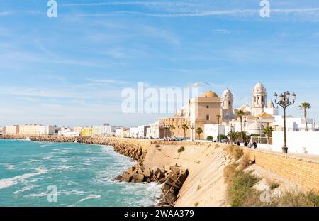 Beautiful view at day of the cathedral of Cadiz called cathedral de Santa Cruz with its 2 towers and its golden dome a blue sky and a blue ocean in Ca Stock Photo
