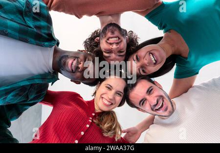 Multiracial group of young people standing in circle and smiling at camera. Stock Photo