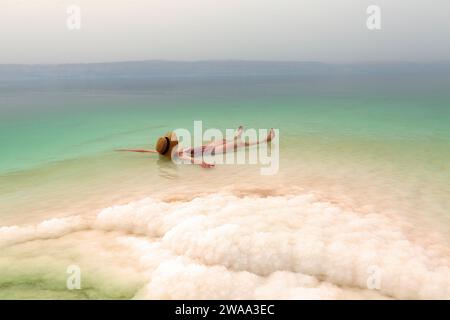 Woman with hat relaxing in salty water of a Dead Sea Stock Photo