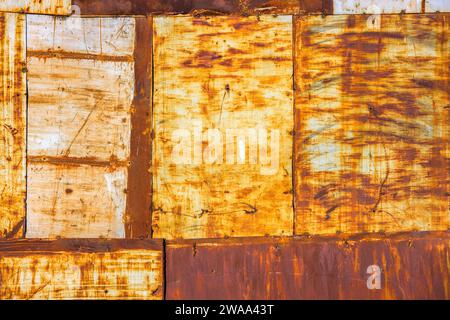 rusty steel sheets welded together wall patchwork with leftovers of faded white paint, closeup full-frame background and texture Stock Photo