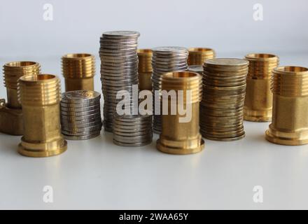 Columns of coins and water high pressure fittings as an illustration of sanitary price Stock Photo