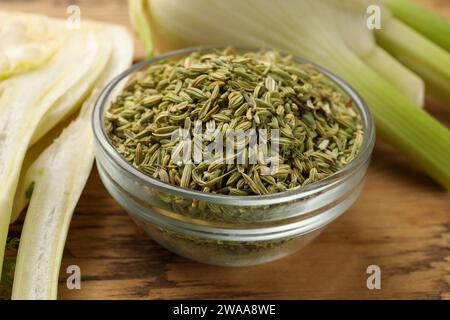 Fennel seeds in bowl and fresh vegetables on wooden table, closeup Stock Photo