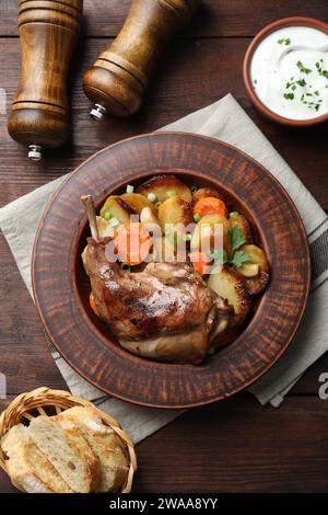 Tasty cooked rabbit meat with vegetables served on wooden table, flat lay Stock Photo