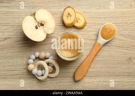 Tasty baby food in jar, teething toy and ingredients on light wooden table, flat lay Stock Photo