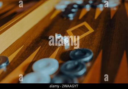 Backgammon board with dice and playing pieces in warm light, shallow depth of field. Stock Photo