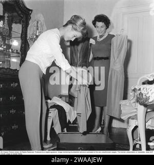 In the 1960s. Two women are packing a suitcase with clothes. 1960 Stock Photo