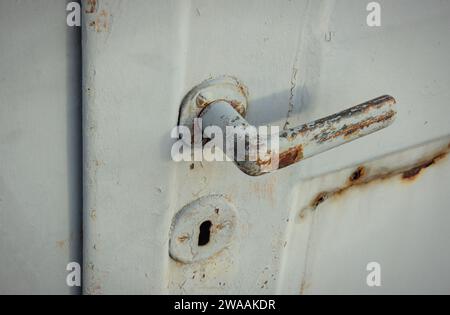 Rusty door opener. Old door latch of a garage. Doorknob with shadows. Stock Photo