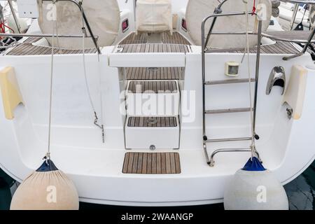 White sailing yacht with teak deck on the quay in marina, view from the stern. Yachting concept. Stock Photo