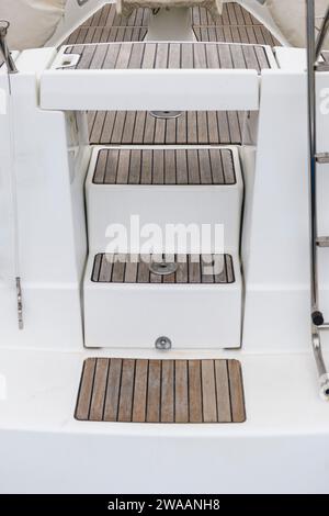 White sailing yacht with teak deck on the quay in marina, view from the stern. Yachting concept. Stock Photo