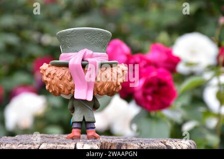 Funko Pop action figure of Mad Hatter from Tim Burton fantasy movie Alice in Wonderland. Back view. Red and white roses, green leaves, garden. Stock Photo