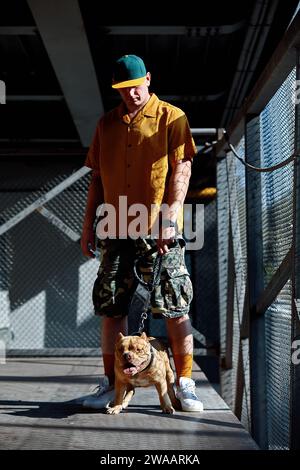 young stylishly dressed man with american bully dog on city streets. Stock Photo