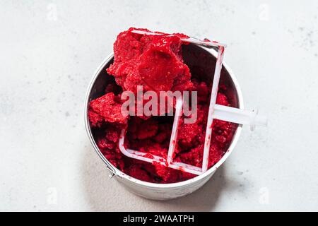 Prepared raspberry sorbet in a big metal bucket in ice cream maker Stock Photo