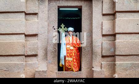 Lalibela, Ethiopia - 24 October 2023: A priest holding christian cross at the entrance of a rock-hewn church at Lalibela, carved from solid rock Stock Photo