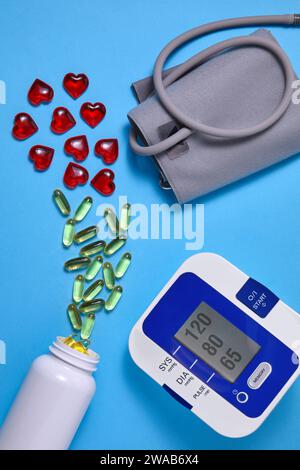 Vitamin D and red decorative hearts and cardiac tonometer on a blue background. Prevention and treatment of atherosclerosis, hypertension and ischemic Stock Photo
