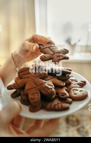 Christmas gingerbread cookies on a white plate in the hands of a man. View from above Stock Photo