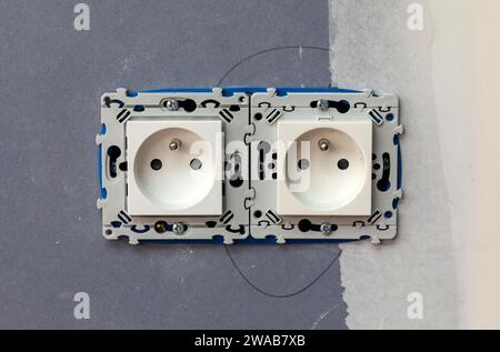 Two-slot electrical outlet socket installation on blue wallboard Stock Photo